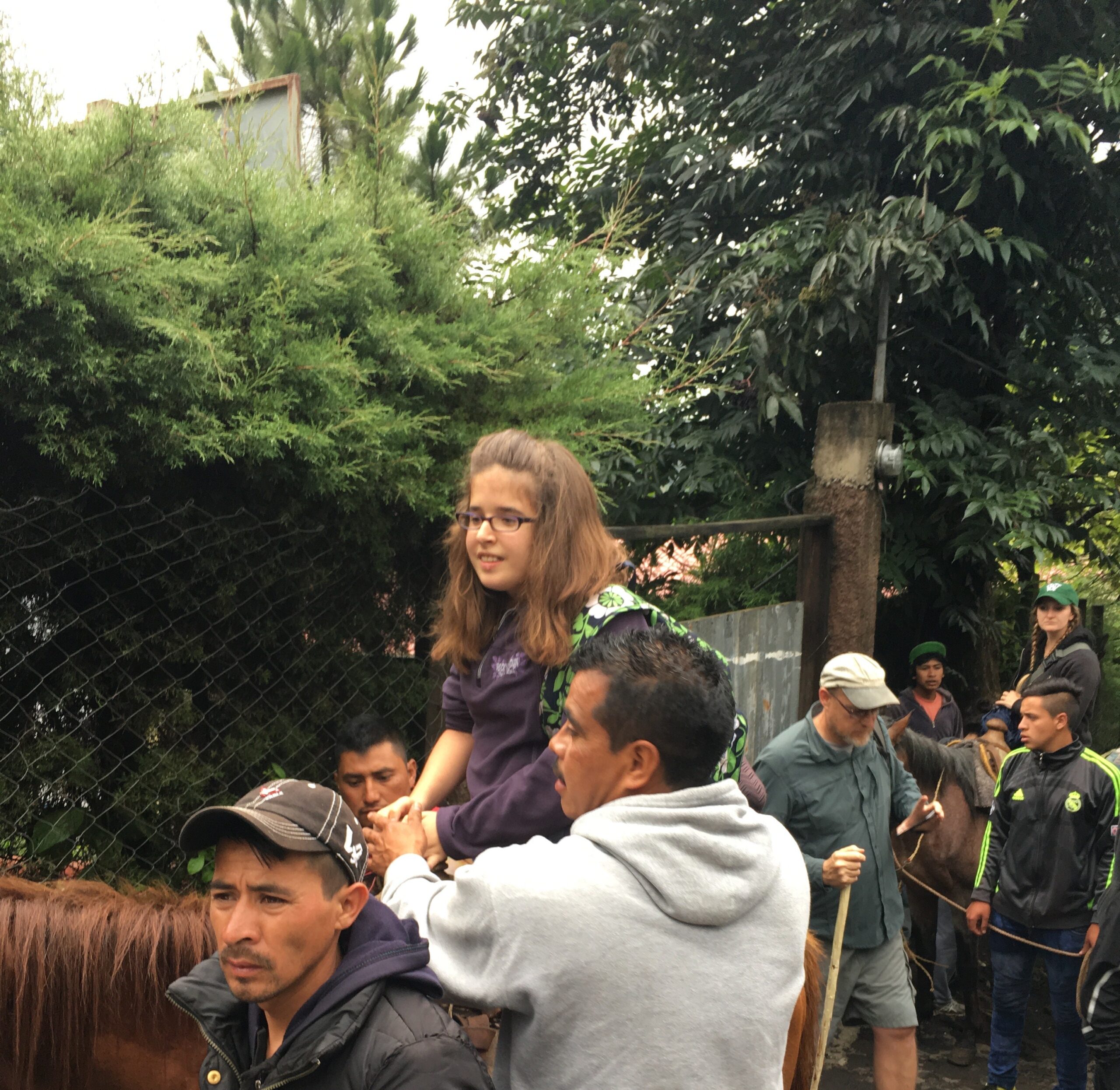 Volunteers help a child on a horse to balance.